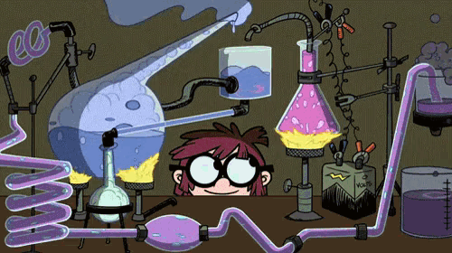 gif de um desenho animado, em que há uma mesa repleta de aparelhos e materiais de laboratório e, atrás da mesa, o rosto de um garotinho de óculos olhando animado para os experimentos