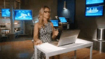 gif de uma mulher, sentada em frente à uma mesa, se preparando para começar a trabalhar no computador